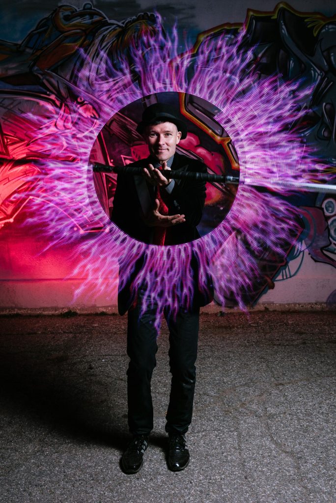 FireGuy showing off an LED spinner that creates what looks like purple fire in a circle around him.