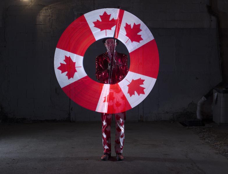 FireGuy dressed in a Canada outfit with a red sequined blazer uses LED spinners to create the Canada Flag.