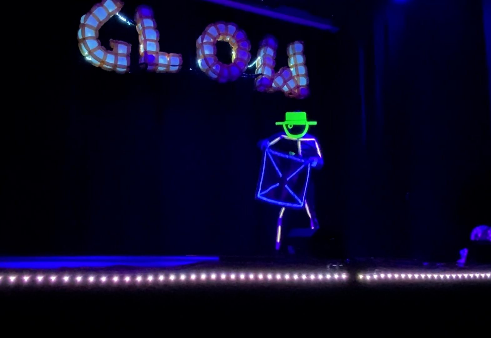 Close up of GlowGuy's stage inside where GlowGuy is holding a small blanket with an LED outline.
