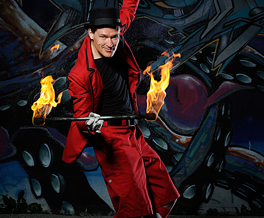 FireGuy during a show presenting his fire baton lit at both ends.